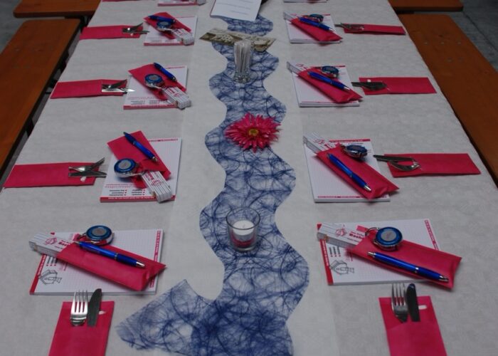Weiß gedeckte Biertischgarnituren mit pinken Servietten und blauer Tischdecke